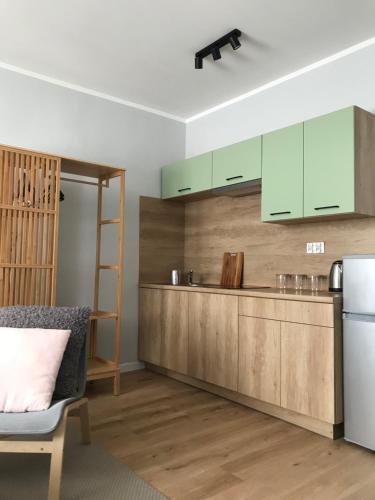 eine Küche mit grünen Schränken und einem Kühlschrank in der Unterkunft Pastelove mieszkanie przy centrum - bezkontaktowo in Bielsko-Biała
