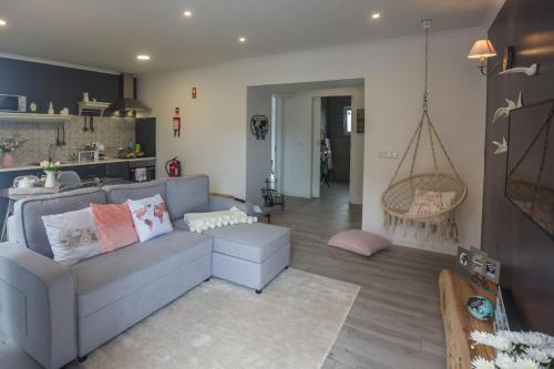 a living room with a gray couch and a kitchen at Bicycle Villas - AL in Ponta Delgada