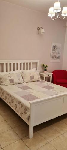 a white bed in a bedroom with a red chair at Soggiorno dell Agnolo in Florence