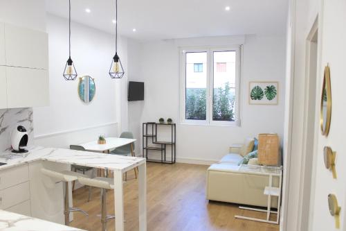 eine weiße Küche und ein Wohnzimmer mit einem Tisch in der Unterkunft CENTRAL NEAR SEA - by SanSebastianApartments·es in San Sebastián