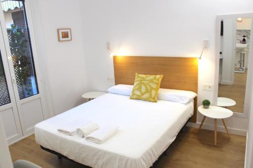 - une chambre avec un grand lit blanc et une tête de lit en bois dans l'établissement CENTRAL NEAR SEA - by SanSebastianApartments·es, à Saint-Sébastien