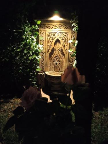 a door with a carving on it in a garden at night at Les Jardins de Ryad Bahia in Meknès