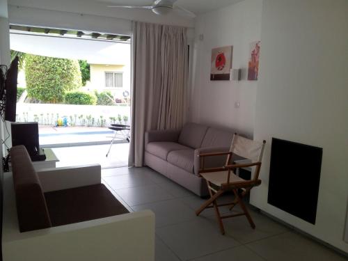 a living room with a couch and a tv at Yialos Holiday Apartments in Pervolia