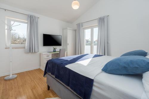 a bedroom with a bed with blue pillows and a television at Villa Camelia in Tar