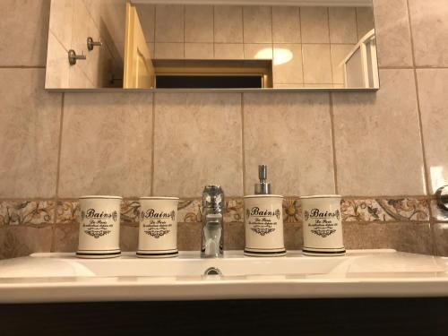 a bathroom sink with four coffee cups on it at Viharsarki Apartman in Gyula