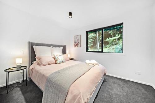 um quarto com uma cama grande e uma janela em Stylish Brand New Apartment - 7 Minute walk to Town em Queenstown