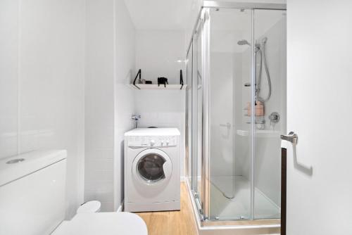 uma casa de banho branca com uma máquina de lavar roupa e um chuveiro em Stylish Brand New Apartment - 7 Minute walk to Town em Queenstown