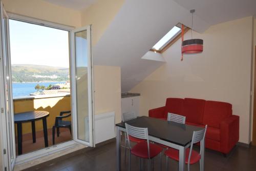 コルクビョンにあるApartamento en la Playa de Quenxeのリビングルーム(赤いソファ、テーブル付)