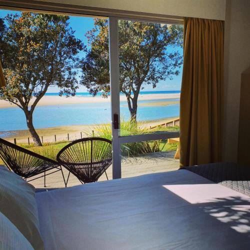 a bedroom with a bed and a view of the beach at Pakiri Beach Holiday Park in Pakiri