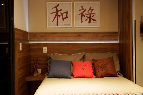 Una cama con tres almohadas encima. en Nakamiti Singular Apart Arujá SP, en Arujá
