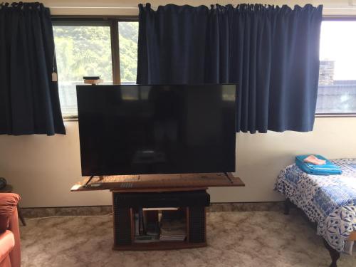 a large flat screen tv on a stand in a living room at Dons Place in Waikawa