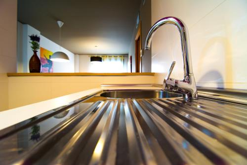 kuchnia ze zlewem z błyszczącym metalowym przedmiotem w obiekcie Apartamentos 16:9 Suites Almería w mieście Almería