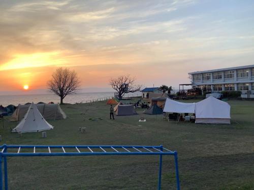 a group of tents in a field with the sunset at YUKUSA OHSUMI UMI no GAKKO in Kanoya