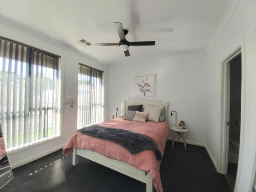 um quarto com uma cama e uma ventoinha de tecto em Lovely Modern 3br 2bth Beachside suburb Home em Largs