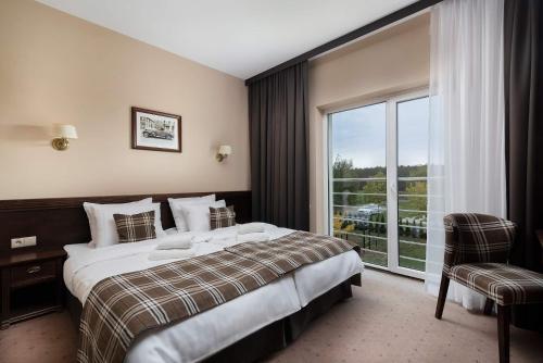 オレシニツァにあるThe Amber Business & Spa Hotelのベッドと大きな窓が備わるホテルルームです。