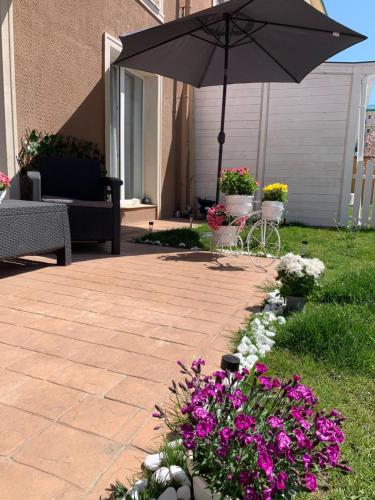 a patio with an umbrella and some flowers at Casa Bella in Ştefăneştii de Jos
