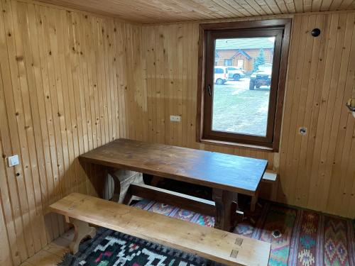 a wooden table and bench in a room with a window at Chalet PidStromom in Mykulychyn