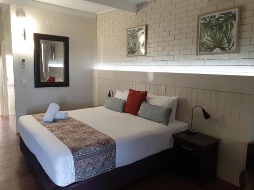 a bedroom with a bed with white sheets and red pillows at The Olive Tree Motel in Morwell