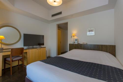 a bedroom with a bed and a desk and a television at Hotel Monterey Ginza in Tokyo