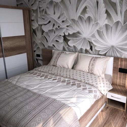 a bedroom with a bed with a floral accent wall at D&N Apartments Синеморец in Sinemorets