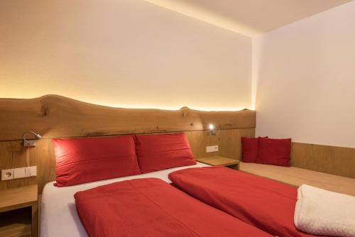 um quarto com uma cama com almofadas vermelhas em Ulrica - Apartment Kristyn em Ortisei