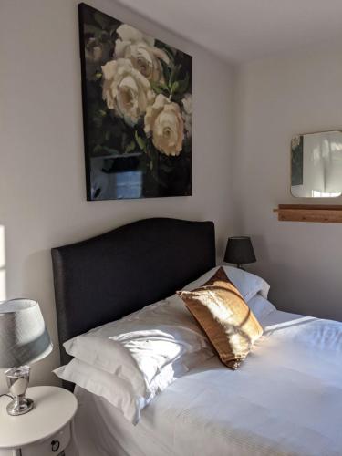 a bedroom with a bed with a painting on the wall at The Saddle Room in Middleham