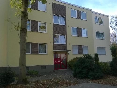 an apartment building with a red door and a tree at Fewo Neukirchen mit Balkon in Neukirchen-Vluyn