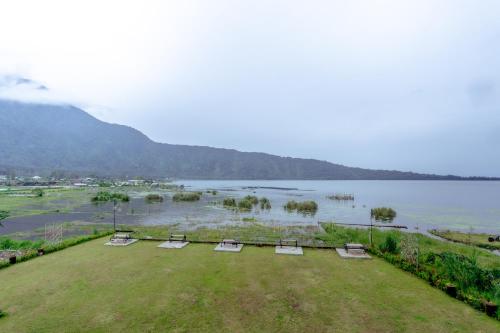 a view of a field with chairs and a body of water at The Joglo Beratan in Bedugul