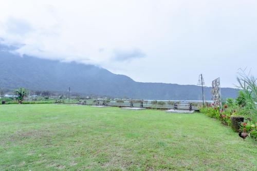 a large grass field with a mountain in the background at The Joglo Beratan in Bedugul