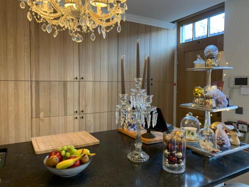 a table with a bowl of fruit and a chandelier at Guestsuite Lady Anna Bruges in Bruges