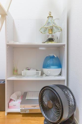 a white book shelf with a fan in a room at japan house Ikebukuro in Tokyo