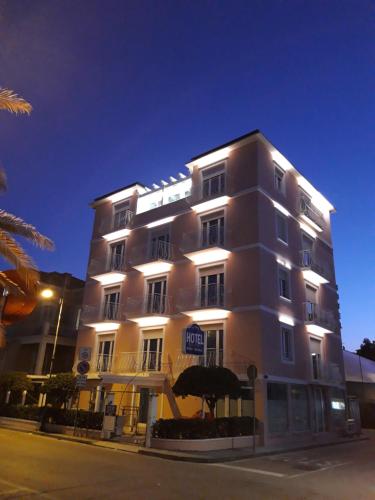 a tall white building with an umbrella in front of it at Hotel Rosa Meublé in Porto San Giorgio