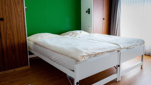 a white bed in a room with a green wall at Metropol in Biel