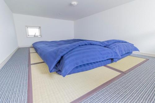 a bed with a blue blanket on the floor at japan house Ikebukuro in Tokyo