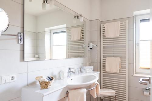 a white bathroom with a sink and a mirror at Land-gut-Hotel Restaurant Kreuz Meyer in Stuhr