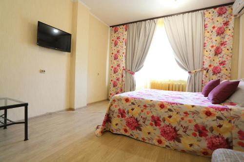 a bedroom with a bed with a floral bedspread and a window at flat-all 61 Kropotkina двухкомнатная квартира до 9 мест рядом с ТРЦ "Галерея Чижова" in Voronezh
