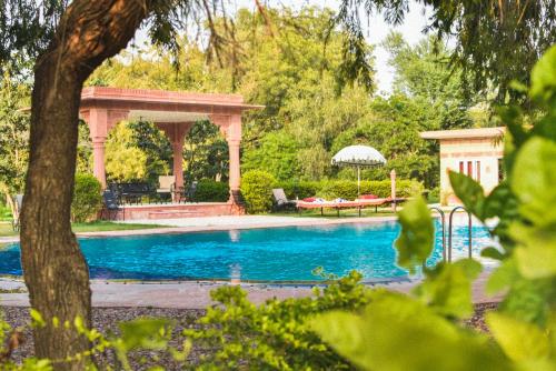 DubbīUmaid Palace - A Lakeside Resort - 25 minutes from Mehandipur Balaji - 20 minutes from Chand Baori Stepwell Abhaneri & 40 minutes from Bhangarh Fort的一个带凉亭和桌子的游泳池