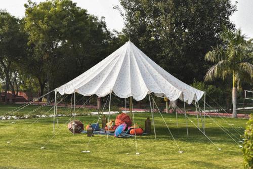 a person sitting under a white tent in a field at Umaid Palace - A Lakeside Resort - 25 minutes from Mehandipur Balaji - 20 minutes from Chand Baori Stepwell Abhaneri & 40 minutes from Bhangarh Fort in Dubbī
