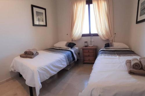 two twin beds in a room with a window at Lovely and luxury apartament in front of the beach in Los Alcázares