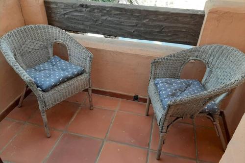 two wicker chairs with blue cushions sitting on a balcony at Lovely and luxury apartament in front of the beach in Los Alcázares
