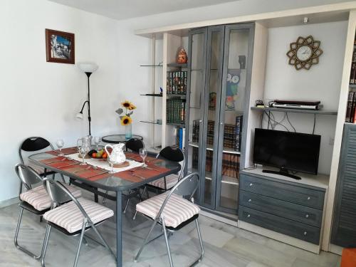 Un comedor con mesa y sillas y un televisor. en Casa Adelfas, Benajarafe, en Benajarafe