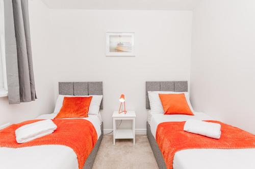 two twin beds in a white room with orange pillows at Burnham House - LABRAD HOMES in Burnham