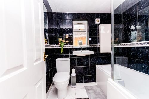a black tiled bathroom with a toilet and a sink at Burnham House - LABRAD HOMES in Burnham