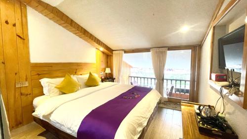 a bedroom with a large bed and a balcony at Bian Cheng Xing Zi Inn in Fenghuang
