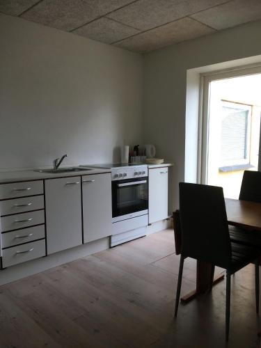 a kitchen with white appliances and a table and a window at Købmandsgården 2 in Sæby