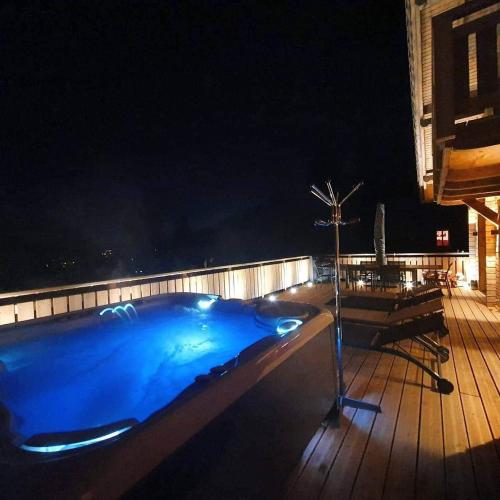 a blue swimming pool on a deck at night at Nouveau Chalet M.META 12 pers sauna,jacuzzi,billard in Xonrupt-Longemer