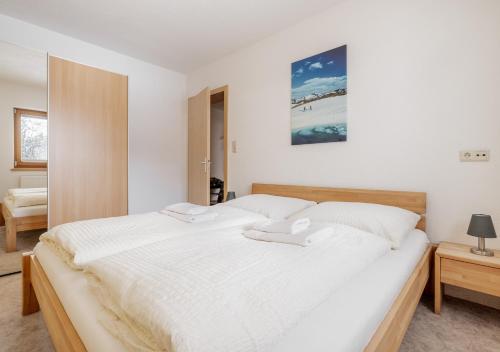 een slaapkamer met een groot bed met witte lakens bij Appartement Marlenka in Umhausen