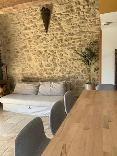 Habitación con mesa de madera y pared de piedra. en Domaine Sesquier Mas d'exception Hibiscus en Mèze