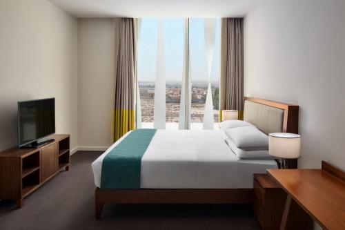 a hotel room with a bed and a television at Staybridge Suites Al Khobar by IHG in Al Khobar