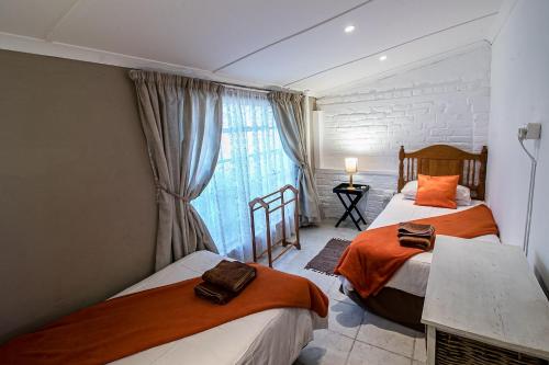 a bedroom with two beds and a window at Eagle's Nest in Graaff-Reinet